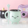 Tasse en forme de chaudron vert menthe avec une baguette pour remuer